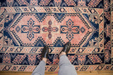 Vintage distressed Melas rug featuring blush quatrefoil and navy geometric border patterns.