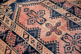 Softened blush pile and navy blue geometric motifs of a distressed vintage Melas rug.