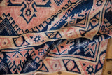 Folded corner of a distressed vintage Melas rug showing blush and navy serrated border.