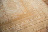 Detail of vintage Oushak rug's distressed texture, faded sand and ivory geometric border.