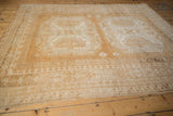 Distressed Oushak rug detail: faded copper gold and beige geometric starburst and border motifs.