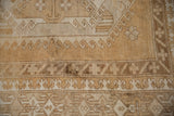 Distressed Oushak carpet texture, even wear, hook and latch motifs in faded beige and sand.