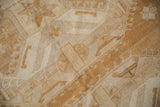 Distressed texture of a vintage Oushak rug with faded copper gold and sand geometric patterns.