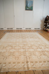 Distressed vintage Oushak carpet, trellis pattern with abrashes in beige, ivory, and coffee tones.