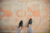Distressed Oushak rug with faded ivory, cantaloupe, and pale blue geometric guls.