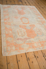 Distressed Oushak rug corner with cantaloupe geometric border and subtle pale blue variations.