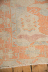 Geometric cantaloupe and ivory motifs on the distressed Oushak rug's even pile.