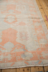 Textured geometric border and fringe of a vintage Oushak rug in cantaloupe and ivory.