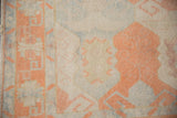 Distressed Oushak rug with geometric cantaloupe border and faded ivory cartouche.