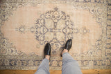 Soft beige and dusty blue tones of a distressed vintage Turkish Sparta rug, showing worn pile.