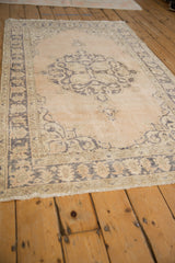 Distressed hand knotted vintage Sparta rug corner, with beige field, dusty blue border, and softly worn texture.