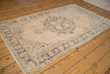 Distressed vintage Turkish Sparta rug corner, showing dusty blue curvilinear border patterns on a beige field.