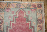 Distressed Oushak rug corner with dusty red stepped motif, tangerine floral border, worn fringe.