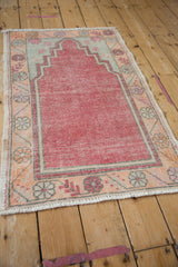 Distressed vintage Oushak rug with muted cherry red field and patterned floral border.