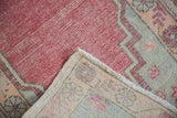 Distressed cherry red Oushak pile with visible foundation and knotted reverse.