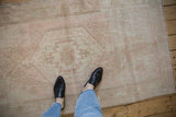 Faded pink and ivory hexagonal medallion on a distressed Oushak rug, with a person.
