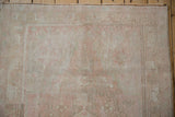 Distressed Oushak rug detail: even pile wear, faded dusty rose blossoms, geometric border.
