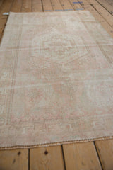 Vintage Oushak rug showcasing distressed texture, faded dusty rose, ivory floral field.