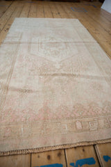 Distressed Oushak rug's softened texture and muted dusty rose, ivory tones.