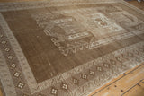 Distressed vintage Kars carpet with geometric wave border and muted brown tones.