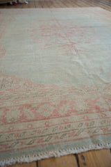Distressed Oushak rug pile with faded pink floral motifs on cream, visible wear.