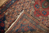 Persian Hamadan runner detail: hand-knotted pile, tattered fringe, woven back.