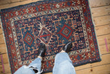 Vintage Persian Karaja rug in navy blue and red shown from an overhead perspective for scale.