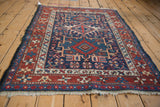 Corner of a vintage Karaja rug showing its red starburst border and dark blue side cord.