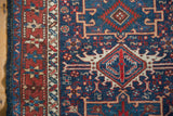 Detail of the vintage Karaja rug's starburst border and geometric navy field, showing the even, low-pile texture.
