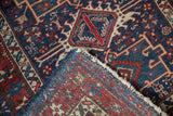 A folded corner of the vintage Karaja rug reveals its hand-knotted back and low navy blue pile.