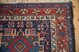 Intricate starburst main border and worn pile on the corner of a vintage Karaja rug.