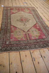 Distressed Hamadan rug corner: faded raspberry red field, corner figures, and patterned borders.