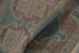 Folded vintage distressed Oushak rug showing pale aubergine, seafoam green, and worn pile texture.