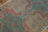 Distressed Oushak pile showcasing muted aubergine and seafoam green geometric patterns.