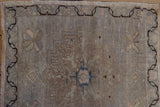 Distressed Oushak rug pile with wavy chocolate brown border and pale blue motifs.