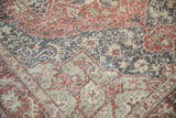 Distressed corner of vintage Sparta carpet with red floral and slate vine patterns.