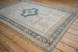 Distressed vintage Oushak rug's dusty dark denim blue reciprocating wave border.