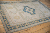 Distressed Oushak rug detail: beige, dusty blue shield medallions, finned birds, wave border.