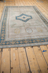 Vintage Distressed Oushak rug close-up, worn pile, dusty blue wave border, hexagonal motifs.