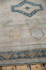 Distressed vintage Oushak rug's textured pile, shield medallions, wave border in beige, blue, gold.