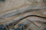 Distressed Oushak rug showing muted beige and dusty blue wave pattern texture.