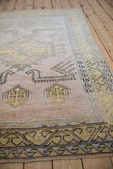 Distressed beige, gold, and blue geometric patterns with shield medallions on a Melas rug.