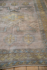 Distressed vintage Melas rug with a gold shield-like geometric medallion and dusty blue border.