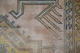 Distressed Melas rug pile with geometric hook and arrow motifs in muted gold and slate blue.