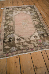 Distressed Oushak rug's floral border and abrashed ground in blush and charcoal.
