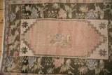 Distressed Oushak detail: abrashed dusty blush field, geometric spandrel, and dark floral main border.