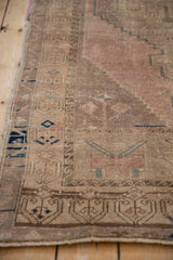 Distressed Oushak runner with faded dusty rose field, muted blue stepped motifs, and worn geometric border.