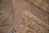Vintage Oushak rug corner with distressed pile, faded rose, beige, and blue geometric patterns.