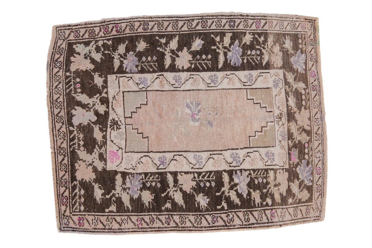 Vintage distressed Oushak rug with a charcoal brown floral border, faded pink field, and stepped corner spandrels.