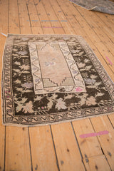 Corner view of a vintage Oushak rug with a charcoal brown floral border and stepped spandrel.